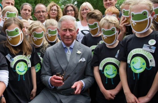 Prince Charles, Prince of Wales poses with a group of school children wearing AArk masks, and an Ecuadorian stream tree frog named in his honour