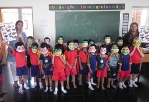 Kindergarten children wearing amphibian masks and holding the South Asian amphibian posters. 